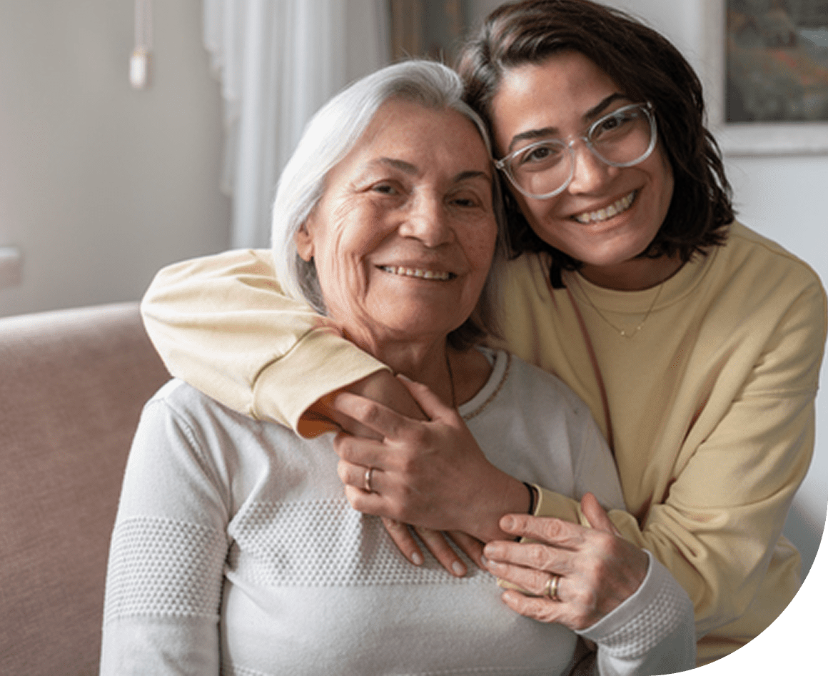 Smiling woman embracing older woman, indoors.