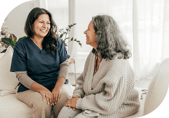 Two women sharing a joyful conversation in a cozy, bright room.
