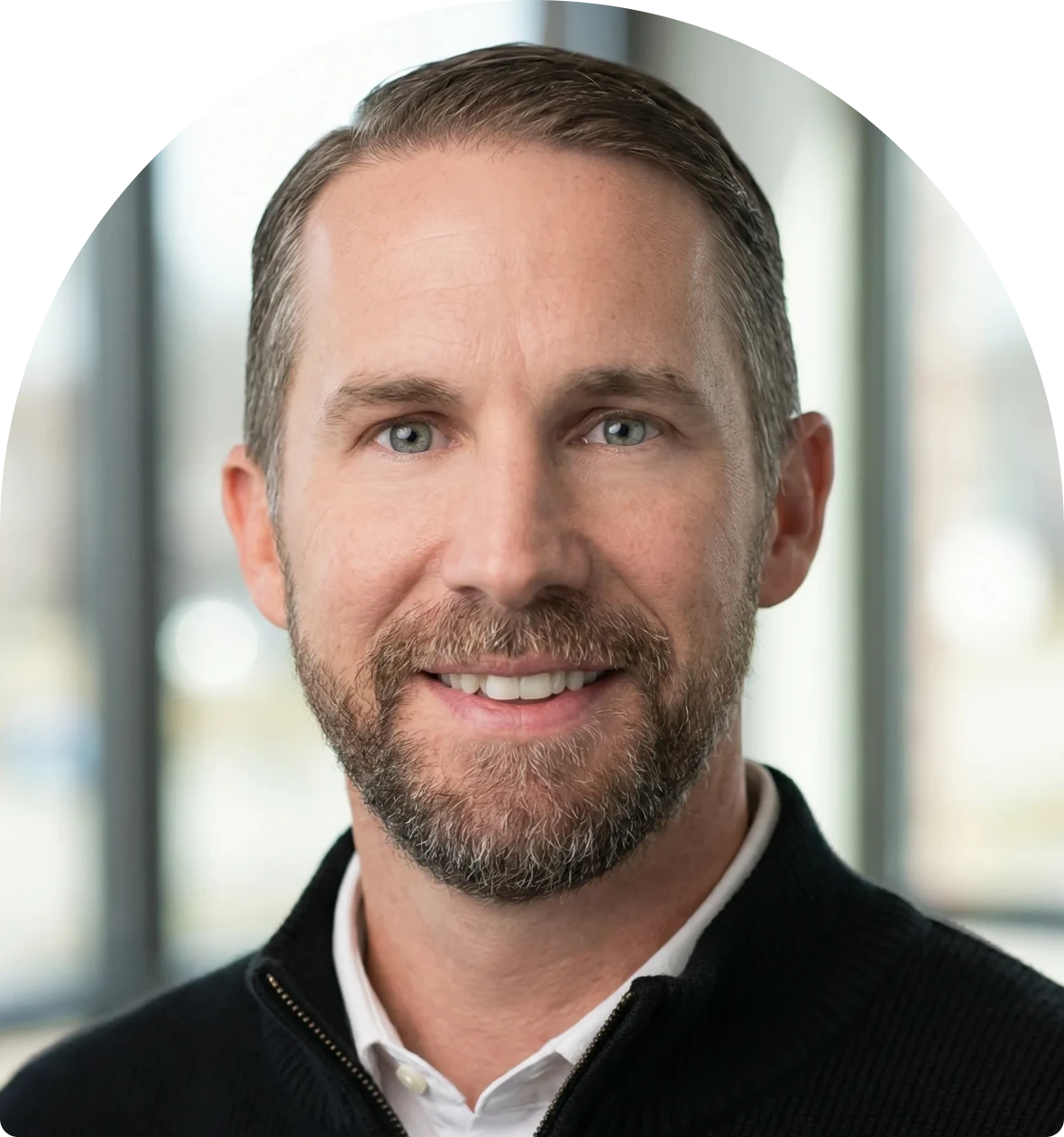 Smiling man with a beard and sweater.