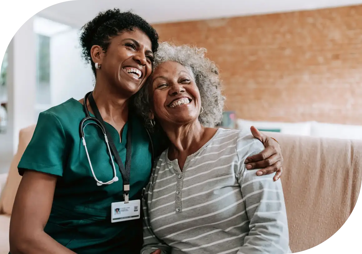 A joyful nurse embraces an elderly woman, sharing a warm moment.