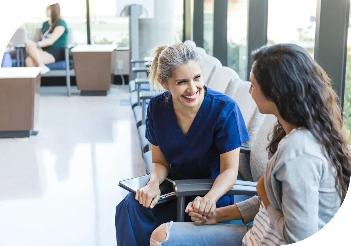 A nurse attentively talking with a patient in a bright medical setting.