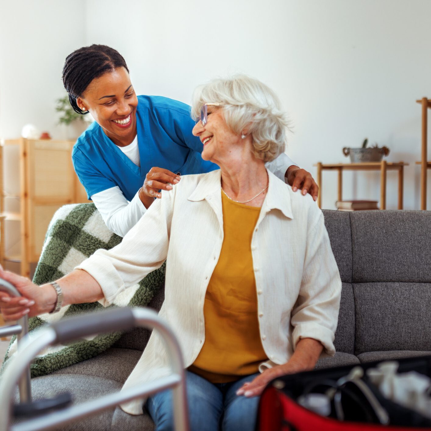 Caregiver assisting elderly woman with mobility aid at home.